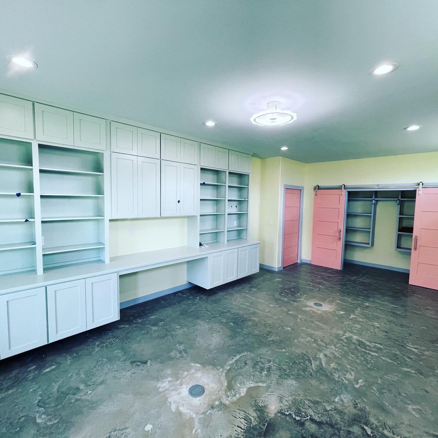 Built-in shelving and desk wall running the length of a room, with sliding barn doors onto a fitted closet