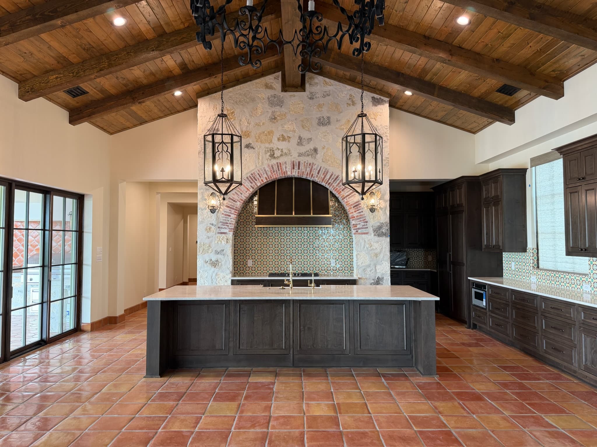 Vaulted kitchen ceiling in stained timber beams and planking above dark stained cabinetry