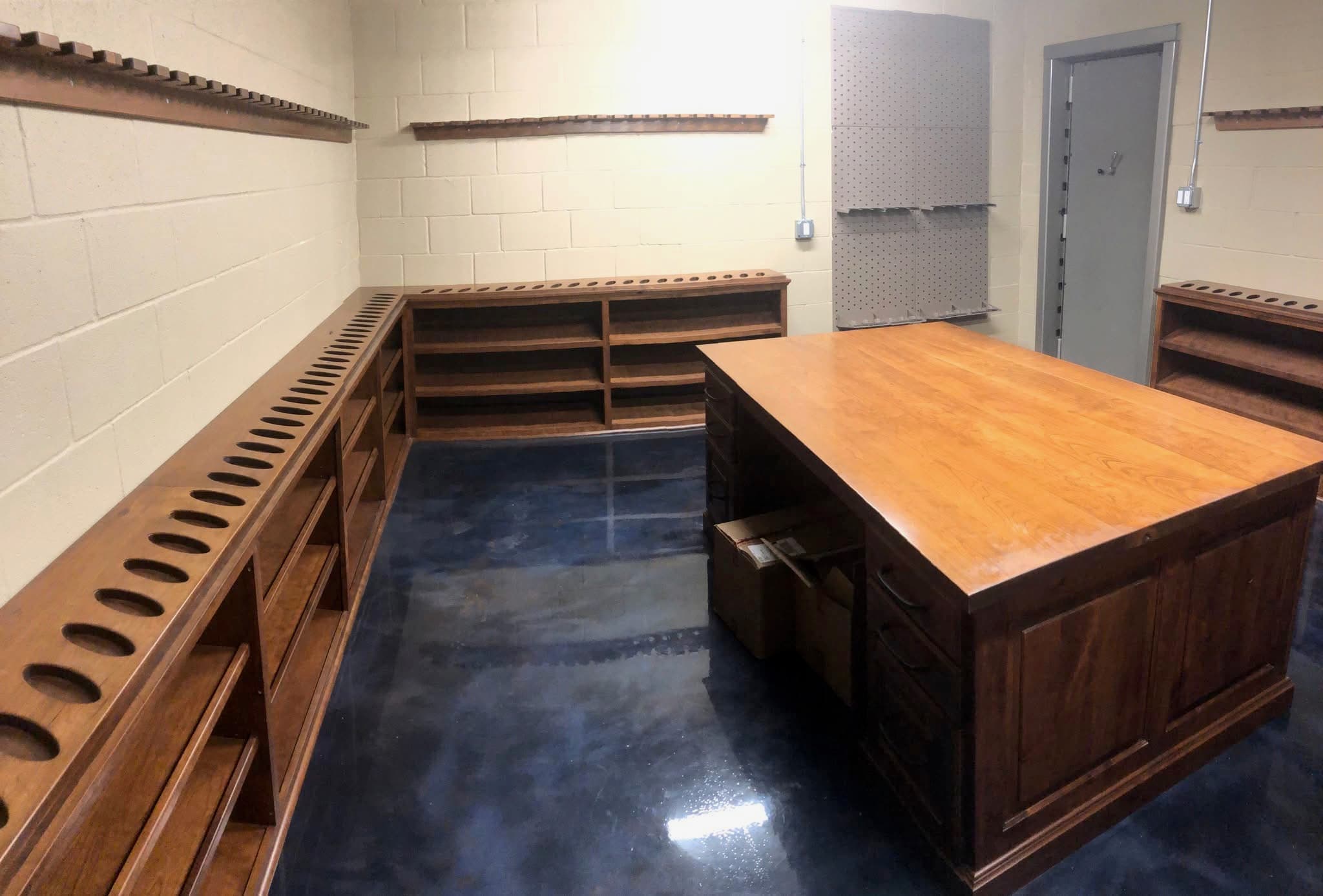 Custom walnut gun room with rifle racks, fitted drawers and a butcher block island