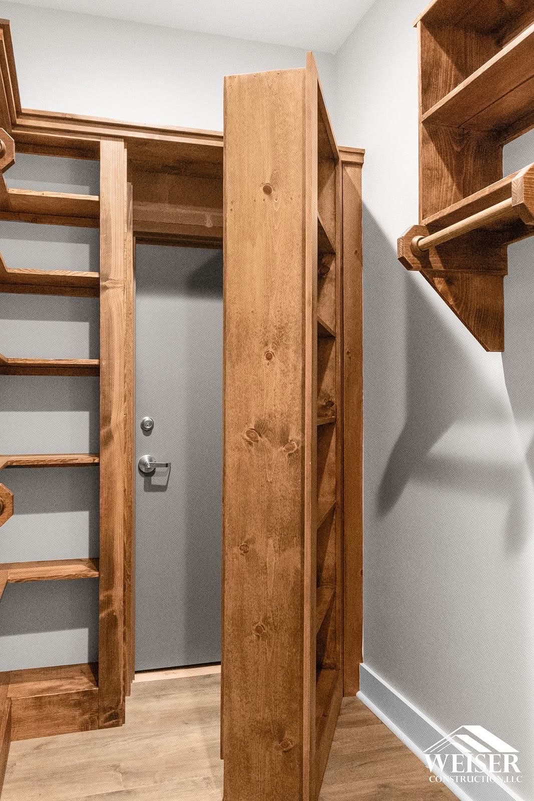 Stained pine bookcase swung open on a concealed hinge to reveal a doorway behind it