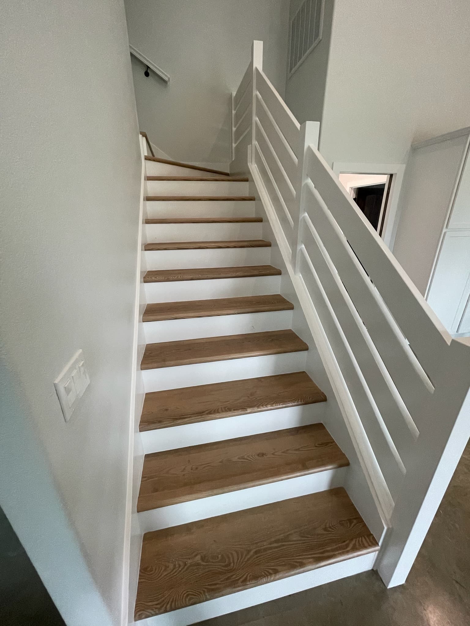 Custom staircase with white oak treads, painted risers and a slatted rail
